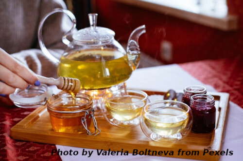 woman pulling honey to pour into tea