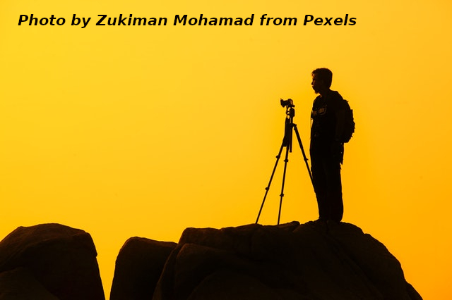 Man on top of rock with camera on a tripod