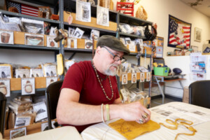 man sewing some kind of pouch