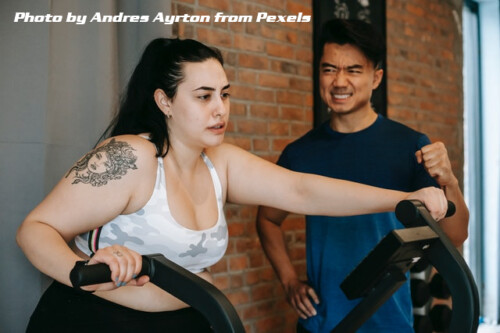 woman on excercise bike with her trainer