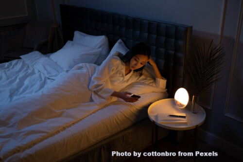 woman in bed looking at cel phone