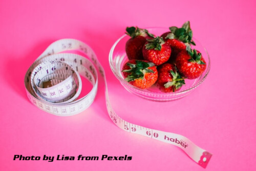 a tape measure and bowl of strwberries