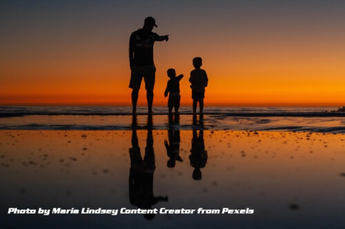 father and soms at seashore sunset