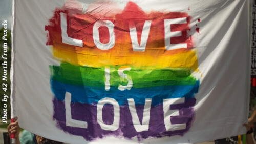 white cloth banner with love is love over LGBTQ colors