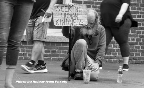 homless man holding sign "seeking human kindness"