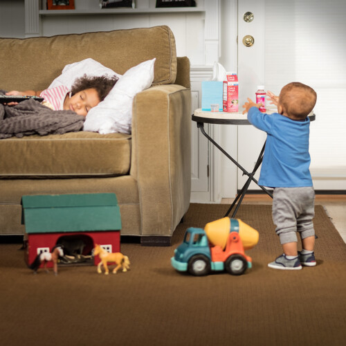 child sleeping on couch and child playing at small table
