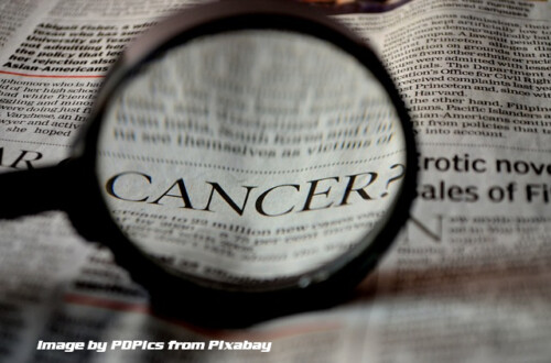 Magnigying glass on newspaper word cancer