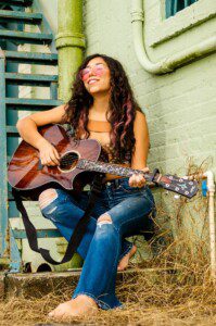 Woman outside on stairs playing guitar