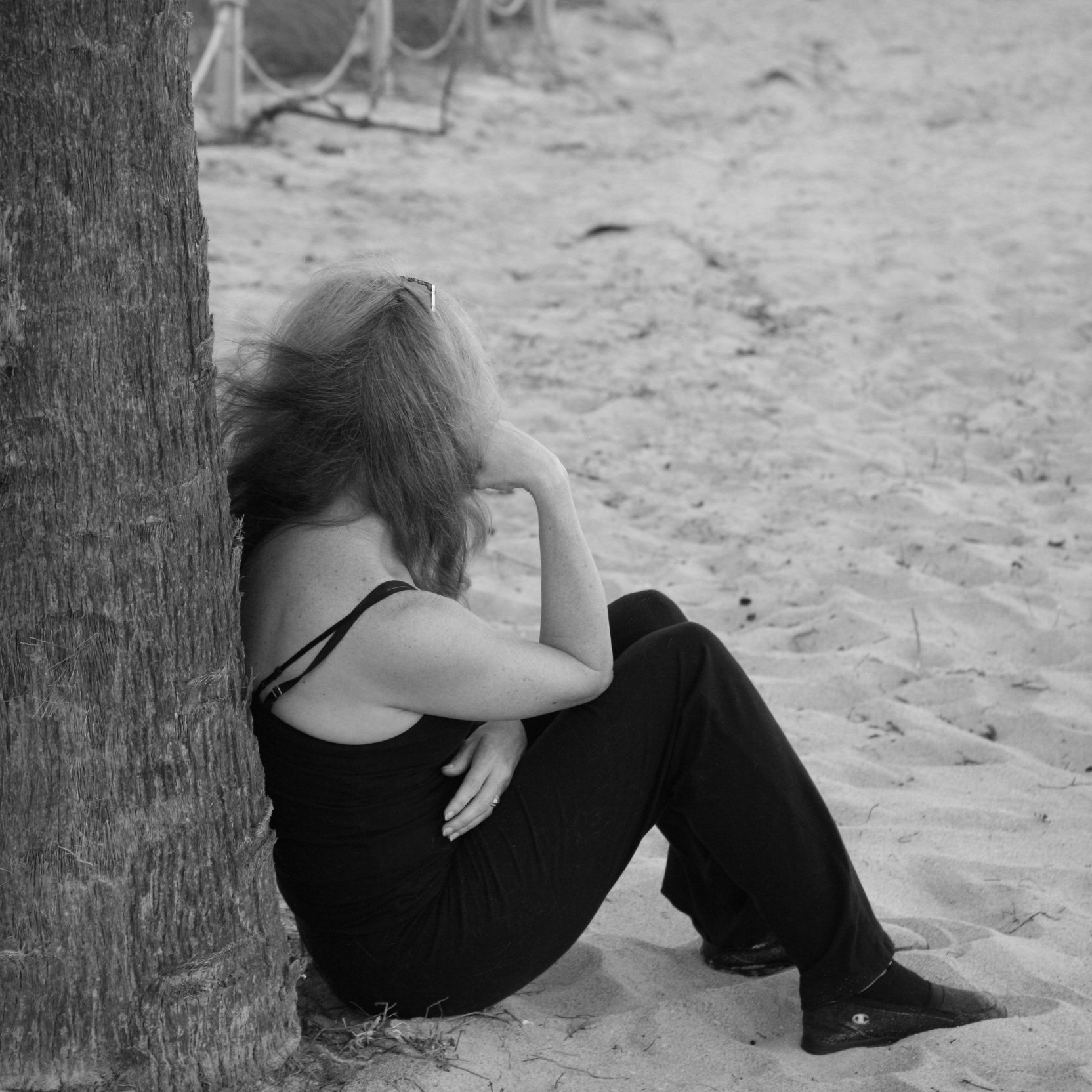 Woman siiting on beach by palm tree