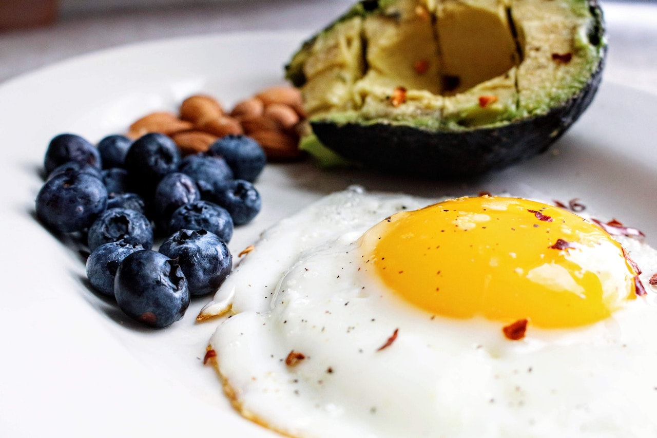 fried egg, avocado and berries on a plate