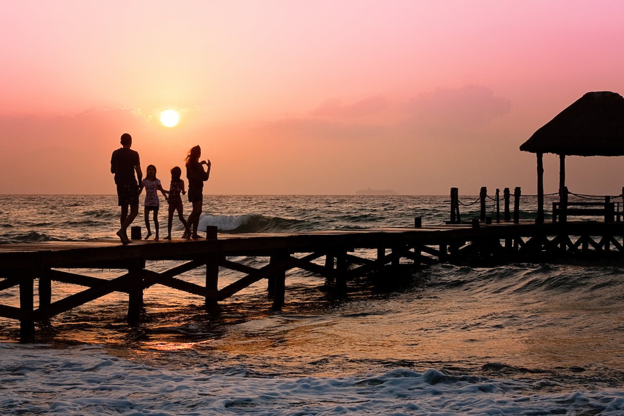 family of four on pier with sunrise in background